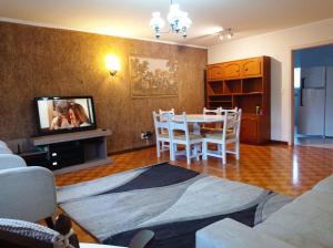sala de estar con mesa, sillas y TV en Amplo e Central Apartamento 3 Quartos, en Gramado