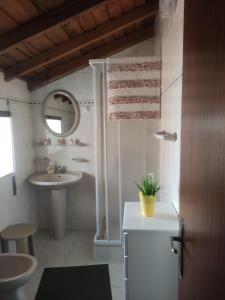 uma casa de banho branca com um lavatório e um espelho em Casa da Cristina na Nazaré