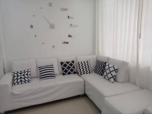 un sofá blanco con almohadas y un reloj en la pared en Apartamento Amoblado en Tacna, en Tacna