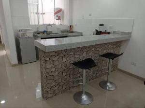 uma cozinha com um balcão de pedra com dois bancos de bar em Apartamento Amoblado en Tacna em Tacna