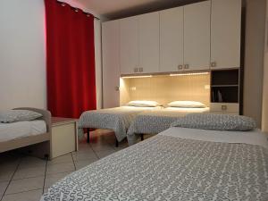 ボローニャにあるAppartamenti Borghetto San Donato 105のベッド2台と赤いカーテンが備わる客室です。