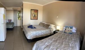 Habitación de hotel con 2 camas y nevera. en Childers Budget Accommodation, en Childers