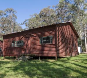 a log cabin with two windows on a grass field at Little Styx River Cabin - The Hilton in Ebor