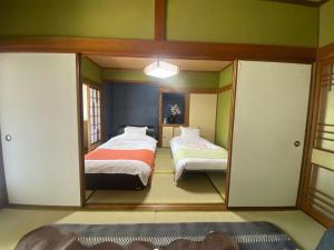 una camera da letto con due letti e uno specchio di 鉄道と山の見える家 a Yufu