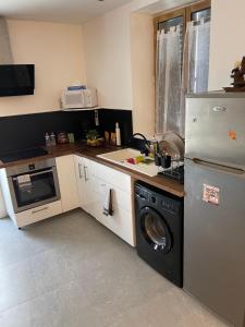 eine Küche mit einem Kühlschrank und einer Waschmaschine in der Unterkunft La maison jacuzzi - Privatiser une soirée jacuzzi in Mandres-les-Roses