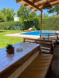 a table and two benches under an umbrella in a yard at Berdina casa estilo loft con jardín, parrilla y cochera a 3 cuadras de la plaza de Chacras de Coria in Chacras de Coria