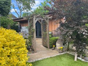 a garden with an arbor and a entrance to a house at Thistle Lodge - Quiet Garden lodge with off road parking in Hemel Hempstead