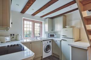 La cuisine est équipée d'un réfrigérateur blanc et d'un lave-vaisselle. dans l'établissement Redwood Cottage, à Nantwich