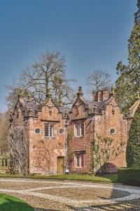 an old brick house with a driveway in front of it at Redwood Cottage in Nantwich