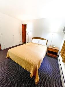 um quarto com uma cama grande e uma colcha amarela em Utica Rest Inn em Utica