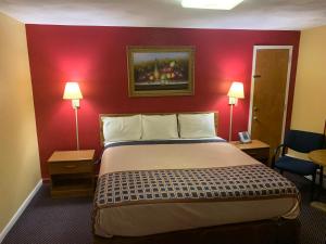 um quarto de hotel com uma cama e uma parede vermelha em Utica Rest Inn em Utica