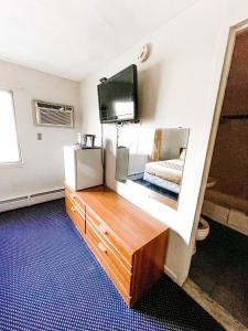um quarto com uma televisão e uma cómoda com um espelho em Utica Rest Inn em Utica