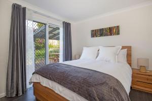 a bedroom with a large bed and a window at WindanSea Cottage Pet Friendly Ocean Glimpses in Vincentia