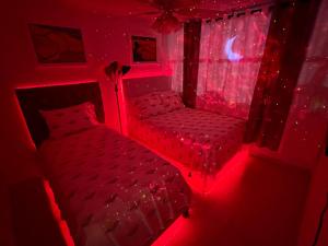 Beachfront Tropical Tantra Apartment في سان خوان: غرفة نوم بسرير وكرسي على ضوء احمر
