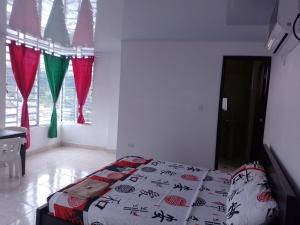 Schlafzimmer mit einem Bett, einem Tisch und Fenstern in der Unterkunft Hostal Apartamentos Delgado in Florencia
