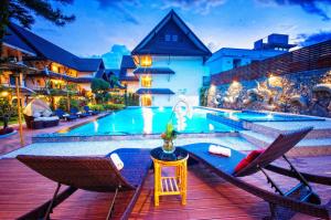 
a patio area with chairs, tables, and umbrellas at Nak Nakara Hotel-SHA Extra Plus in Chiang Rai
