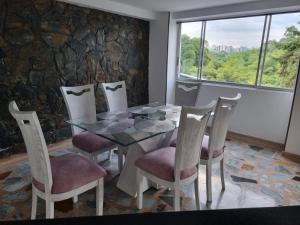 comedor con mesa de cristal y sillas en Pent House La Castellana, en Armenia