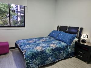 1 dormitorio con cama con sábanas azules y ventana en Pent House La Castellana, en Armenia