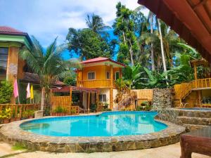 a swimming pool in front of a house at Stefanie Grace Inn in Loboc