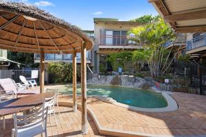 une piscine avec un parasol, une table et des chaises dans l'établissement MAIN STAY - 100m to patrolled beach, pool, wifi, close to cafes, à Point Lookout