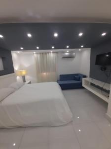 a bedroom with a large white bed and a blue couch at Hermoso apartamento Residencial madera I in Santiago de los Caballeros