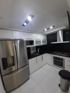 una cocina con armarios blancos y electrodomésticos de acero inoxidable en Hermoso apartamento Residencial madera I en Santiago de los Caballeros