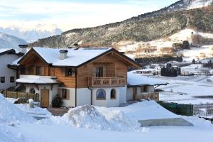 a house covered in snow with mountains in the background at Agritur La Val in Vigolo Vattaro