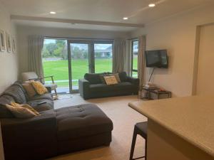 - un salon avec un canapé et une télévision dans l'établissement On The Green - Pauanui Holiday Home, à Pauanui