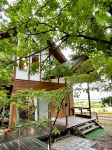 una casa con terraza de madera en el bosque en びわ湖ハイドアウト en Takashima
