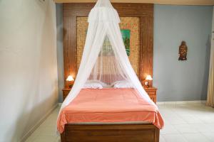 a bedroom with a bed with a mosquito net at Orange Balangan Bungalow in Uluwatu +59 photos