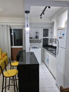 a kitchen with white appliances and a black counter top at Apartamento na praia de Jatiúca com piscina e área de lazer in Maceió
