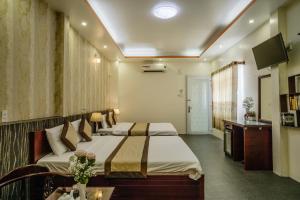 a hotel room with two beds and a television at Dong Bao Hotel in Chau Doc