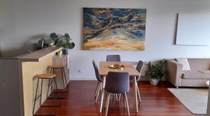 a living room with a table and chairs and a painting at beautiful apartment 100mts near the beach in Port Melbourne in Melbourne