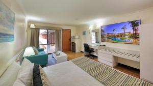 um quarto de hotel com um quarto com uma cama e uma secretária em The Palms Dubbo em Dubbo