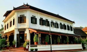 a white building with plants in front of it at Saynamkhan River View in Luang Prabang