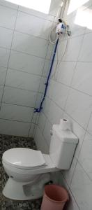 a bathroom with a white toilet and a blue hose at Lucky777 Homestay in Mambajao