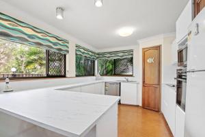 a kitchen with a large white counter and windows at Sha na na Unit 3 Kings Beach Gem in Caloundra