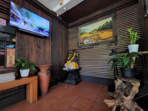 um quarto com uma televisão numa parede com plantas em Mai Malu em Pulukan