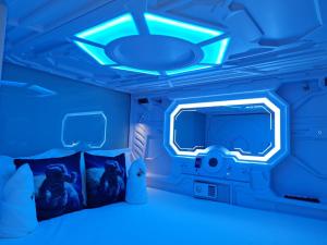 a blue room with a bed and a tv at Galaxy Pods Capsule Hotel Boat Quay in Singapore