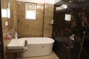 a bathroom with a bath tub and a sink at Hotel Palm Bliss International in Dānāpur