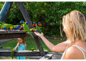 a woman is holding a bird in her hand at Discovery Parks - Airlie Beach in Airlie Beach