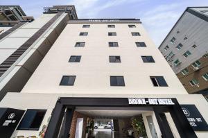 a tall white building with a sign on it at Brown-Dot Hotel Geomdan in Incheon