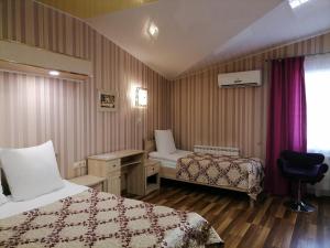 Cette chambre comprend deux lits, un bureau et une chaise. dans l'établissement Khutorok Hotel, à Ulan-Ude