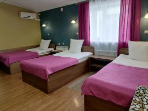 Habitación con 2 camas con sábanas rosas y ventana. en Khutorok Hotel, en Ulan-Ude