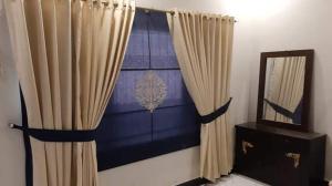 a room with a curtain and a mirror and a dresser at Hotel Royal Defence in Lahore