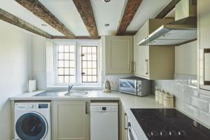 a kitchen with a sink and a washer and dryer at Lakeside Cottage in Nantwich