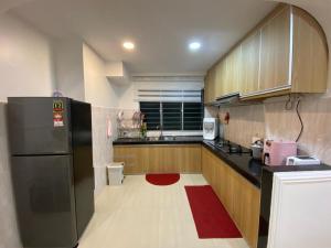 a kitchen with a black refrigerator and a red rug at Teratak Nenda in Ampang