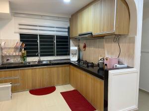 cocina con armarios de madera, fregadero y ventana en Teratak Nenda, en Ampang