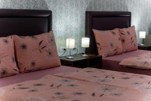 a bedroom with two beds with pink sheets and lamps at Hostel Antique in Pula