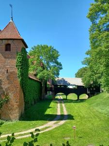 an old brick building with a pathway in the grass at Apartament Zamkowy in Malbork
